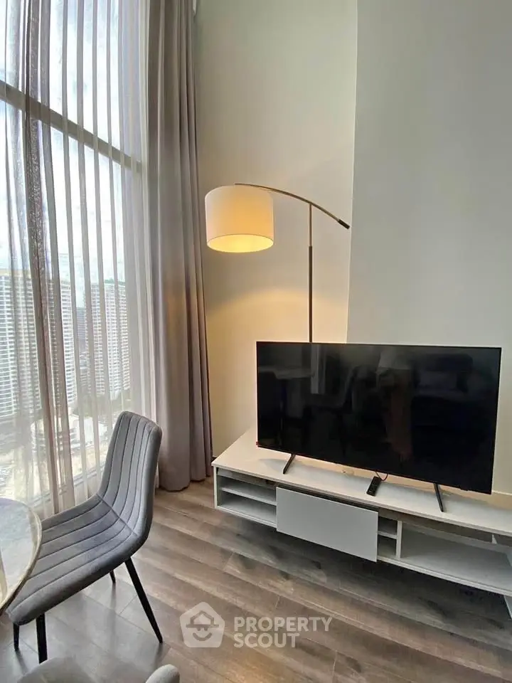 Modern living room with floor-to-ceiling windows, sleek TV stand, and stylish chair in a high-rise apartment.