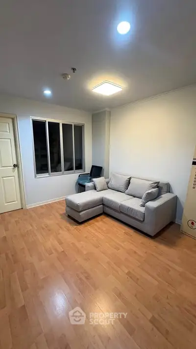 Cozy living room with modern sofa and wooden flooring, perfect for relaxation.