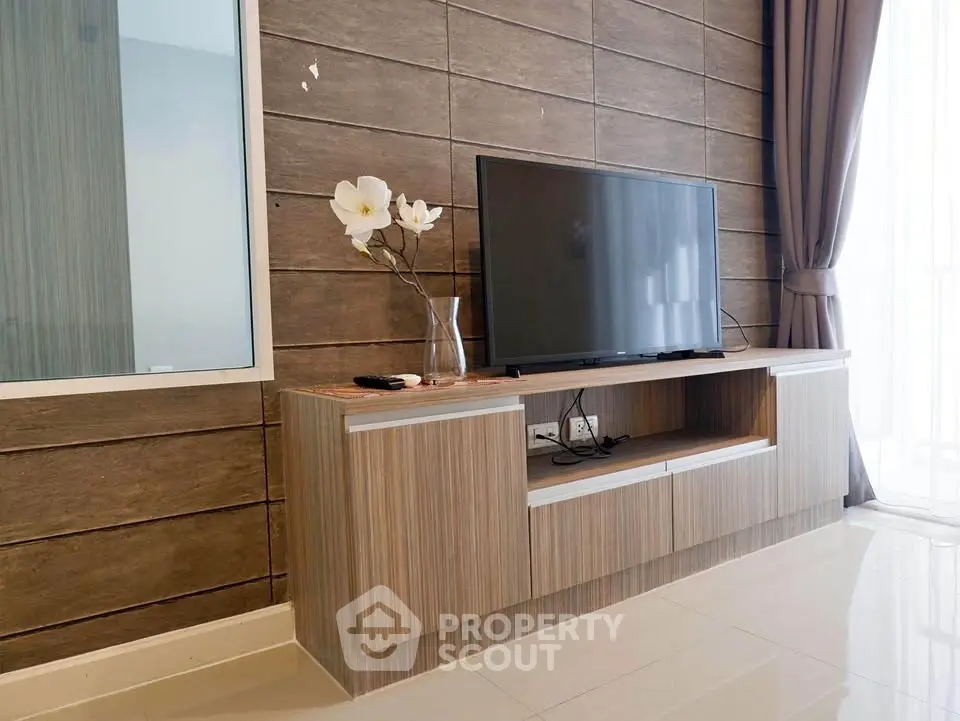 Modern living room with sleek TV stand and large flat-screen TV, featuring elegant decor and natural light.
