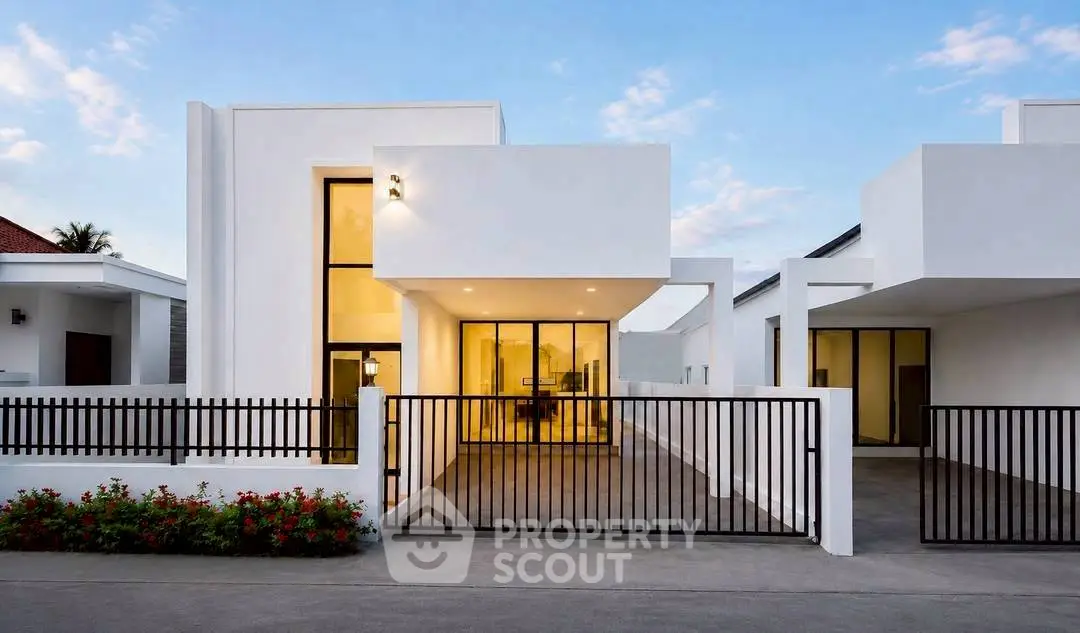 Modern minimalist white house with large windows and sleek black gate under a clear blue sky.