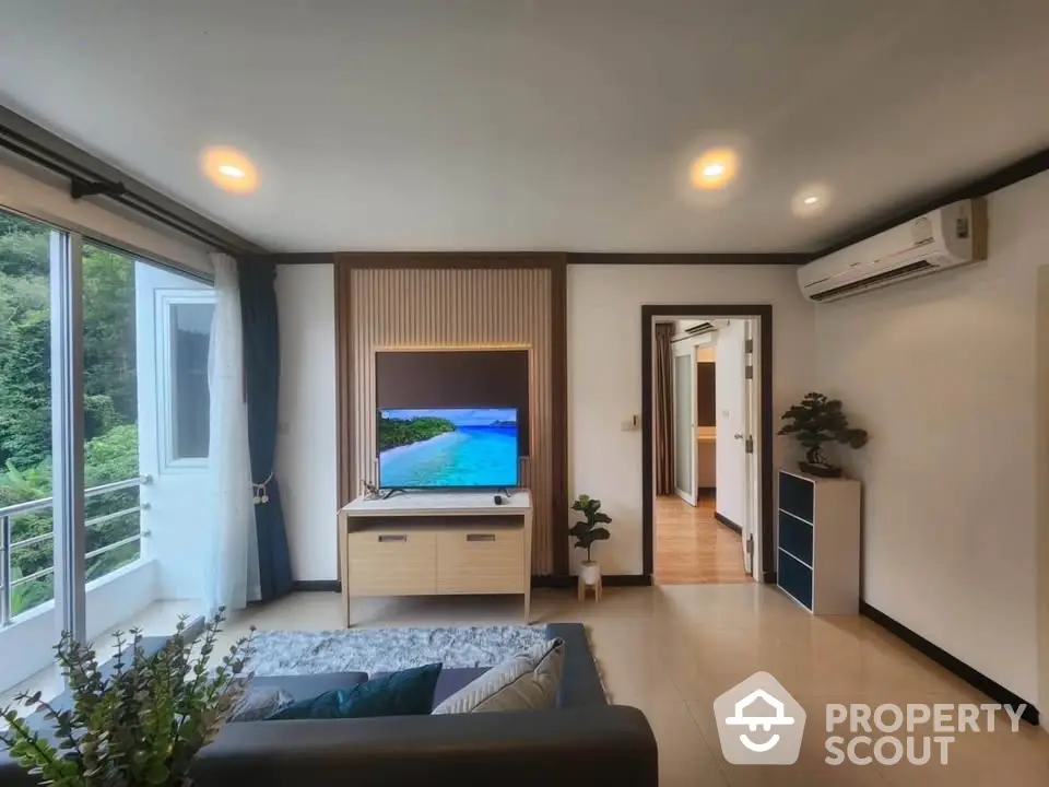 Modern living room with balcony and scenic view, featuring stylish decor and natural light.