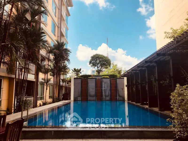 Luxurious apartment complex with serene outdoor pool and lush greenery.