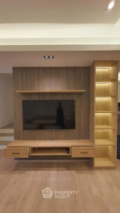 Modern living room with stylish wooden TV unit and shelving