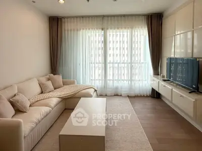 Modern living room with cozy sofa and large TV, featuring elegant curtains and natural light.