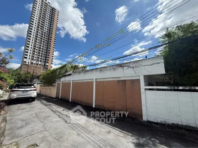 Urban alleyway with tall building and parked car under clear blue sky