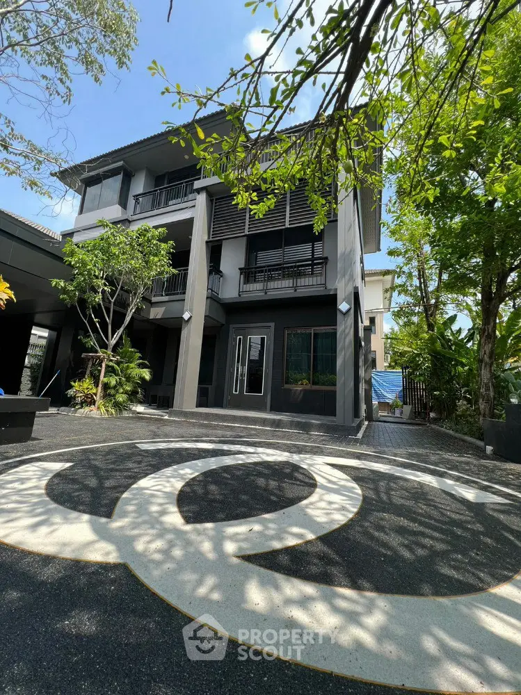 Modern three-story building with unique circular driveway and lush greenery