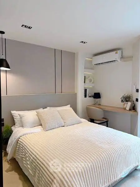 Modern bedroom with cozy bed and stylish workspace, featuring air conditioning and elegant decor.