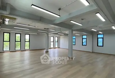 Spacious open-plan office space with large windows and modern lighting.