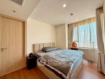 Modern bedroom with large window and cozy decor in a high-rise apartment.