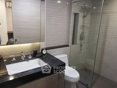 Modern bathroom with glass shower and sleek vanity in luxury apartment.