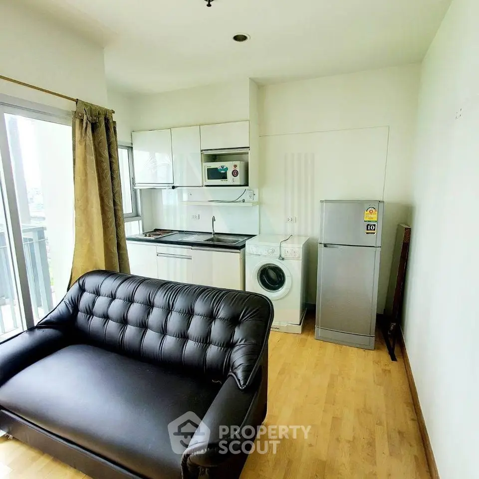 Modern studio apartment with compact kitchen and cozy living area, featuring a fridge and washing machine.