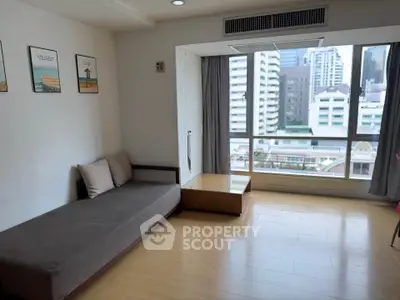 Spacious living room with large window offering city view, modern decor, and comfortable seating.