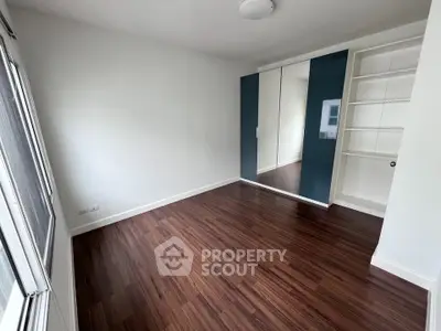 Spacious bedroom with wooden flooring and built-in wardrobe, perfect for modern living.