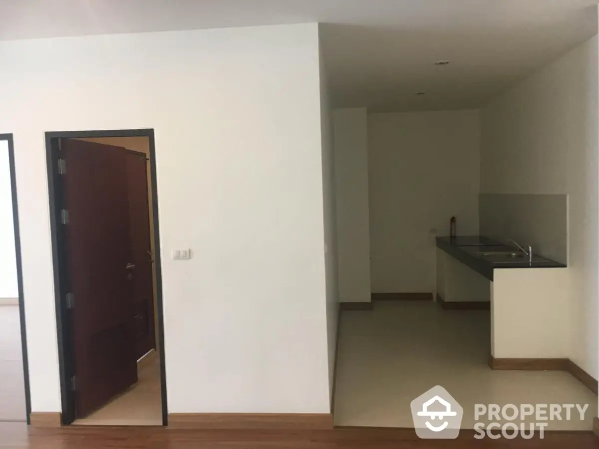 Spacious apartment interior with open kitchen layout and wooden flooring, ideal for modern living.