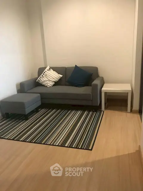 Cozy living room with modern sofa and striped rug, perfect for relaxation.