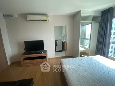 Modern bedroom with TV, air conditioning, and city view in high-rise apartment.
