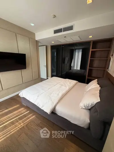 Modern bedroom with sleek design, featuring a comfortable bed, built-in wardrobe, and wall-mounted TV.