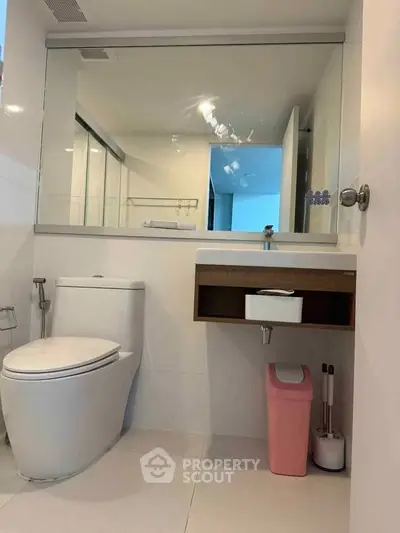 Modern bathroom with sleek fixtures and large mirror in a contemporary home.