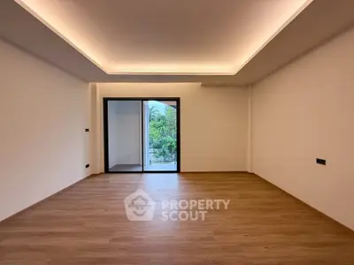 Spacious modern living room with wooden flooring and large window offering scenic views.