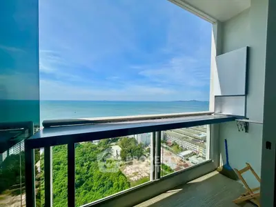 Stunning ocean view from high-rise balcony with glass railing and clear blue skies.