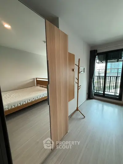 Modern bedroom with large window and wooden furniture, featuring a sleek design and ample natural light.