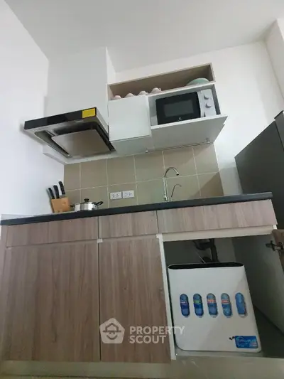Modern kitchen with microwave, stove, and sleek cabinetry in compact layout.
