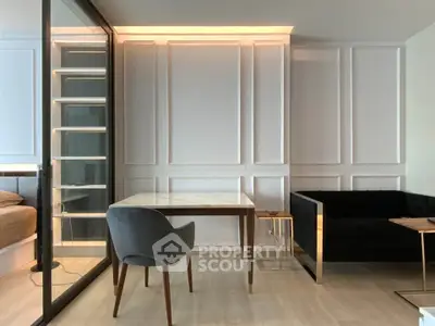 Modern living room with elegant paneling, glass partition, and stylish furniture in a contemporary apartment.