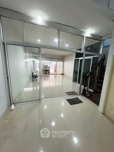 Spacious modern interior with glass doors and elegant staircase, perfect for contemporary living.