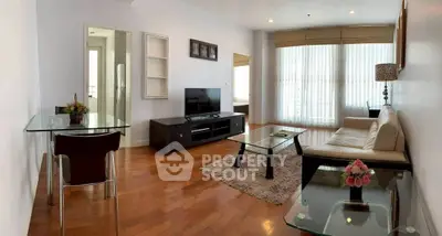 Spacious modern living room with hardwood floors, large windows, and stylish furniture in a bright apartment.