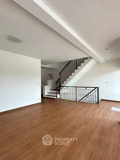 Spacious modern living room with elegant staircase and wooden flooring.
