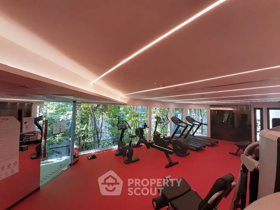 Modern gym with large windows and red flooring in luxury building