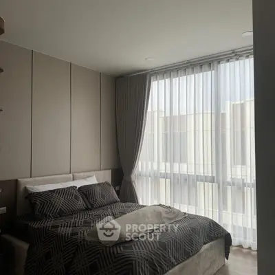 Modern bedroom with large window and stylish decor in a contemporary apartment.