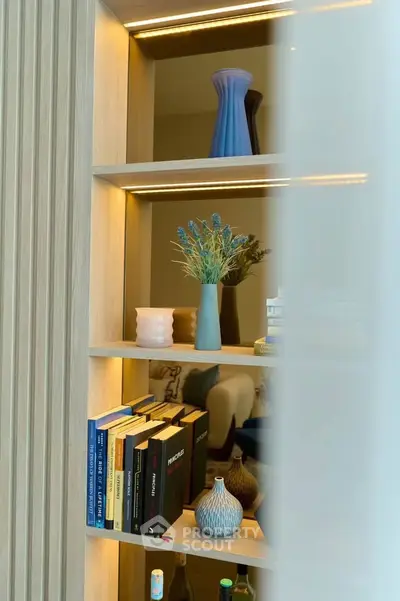 Stylish interior shelf with books and decorative vases in modern living room.