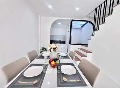 Elegant dining area with modern staircase and sleek kitchen in open layout