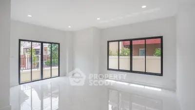 Spacious empty living room with large windows and glossy white floors