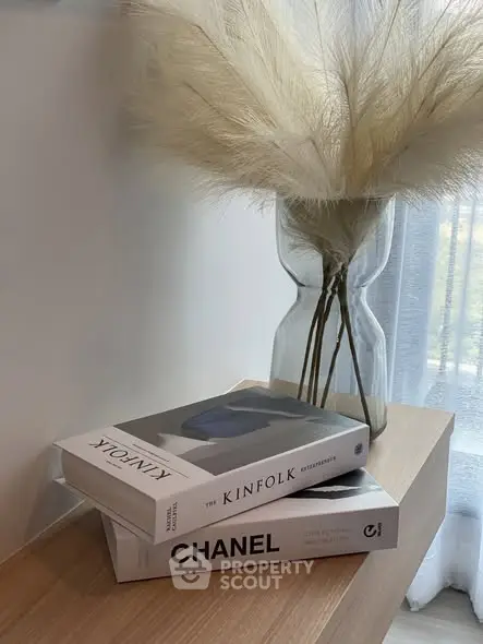 Stylish interior decor with books and vase on wooden table near window.