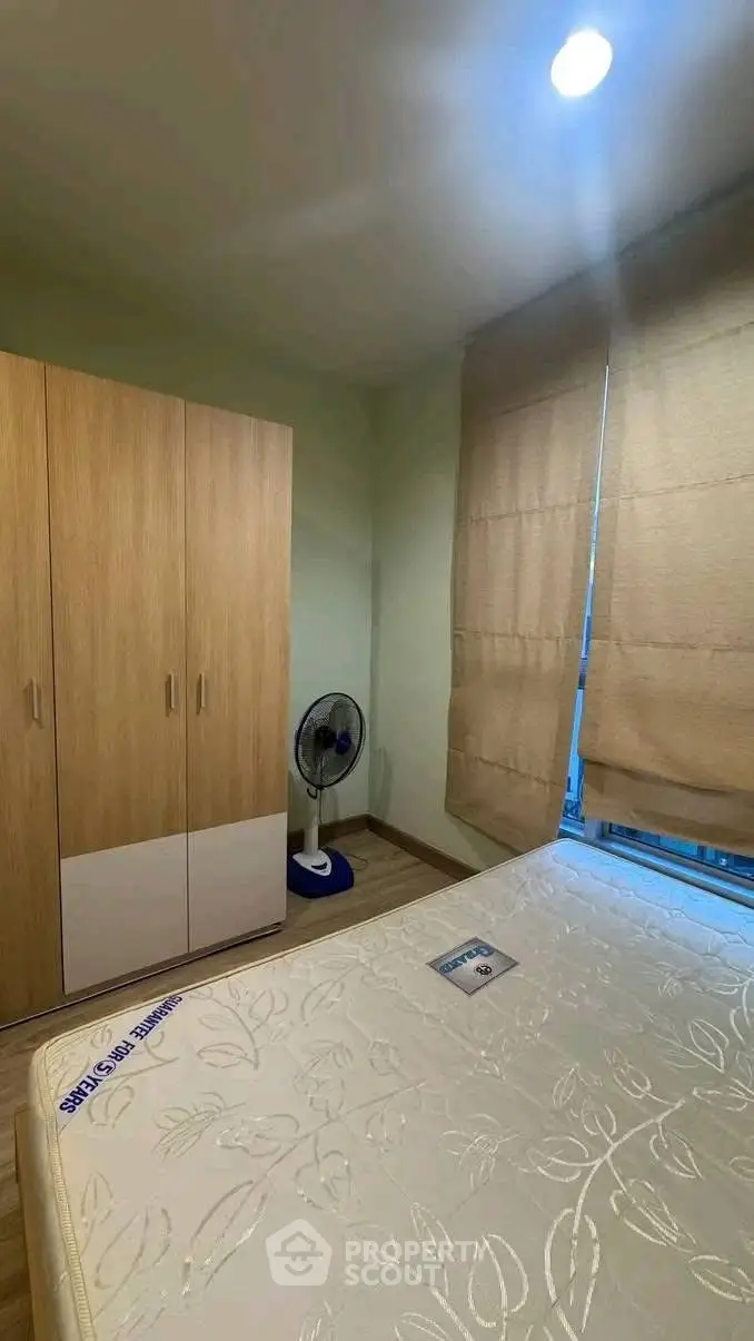 Cozy bedroom with wardrobe and fan, featuring a comfortable mattress and soft lighting.