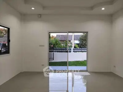 Spacious modern living room with large sliding glass doors opening to a lush garden view.