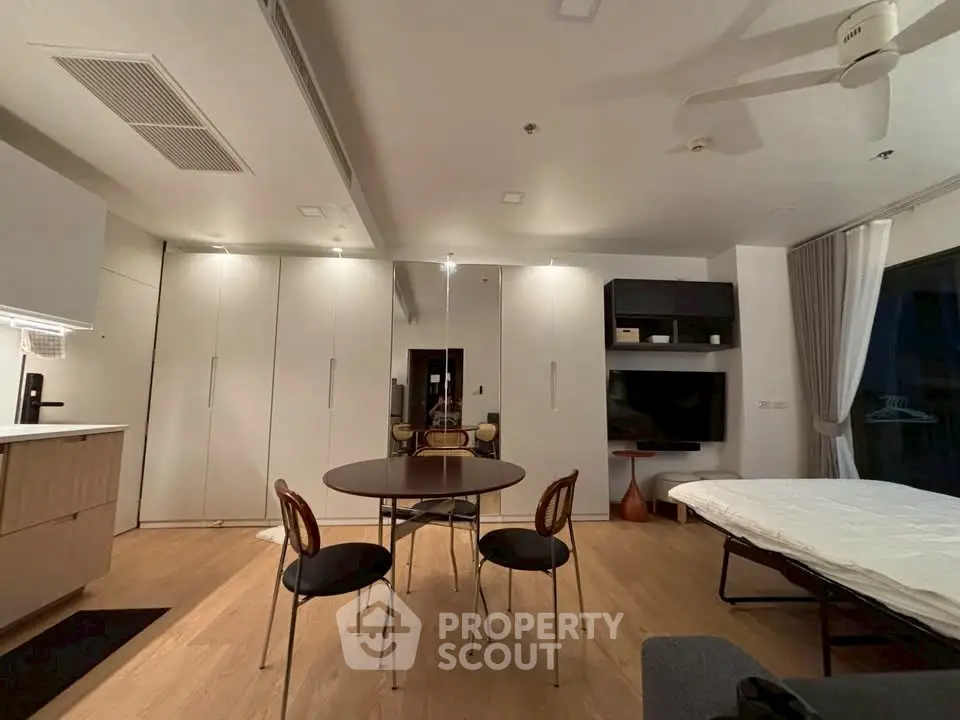 Modern living room with sleek furniture and open layout, featuring a round dining table and stylish chairs.