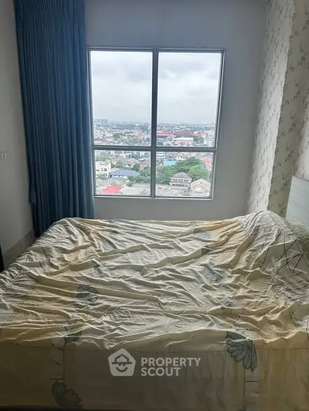 Cozy bedroom with large window offering a stunning city view, perfect for relaxation.