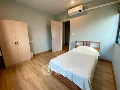 Cozy bedroom with wooden flooring and modern air conditioning unit, perfect for comfortable living.