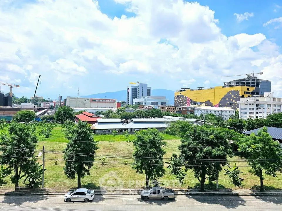 Scenic cityscape view with lush greenery and modern buildings under a bright blue sky.
