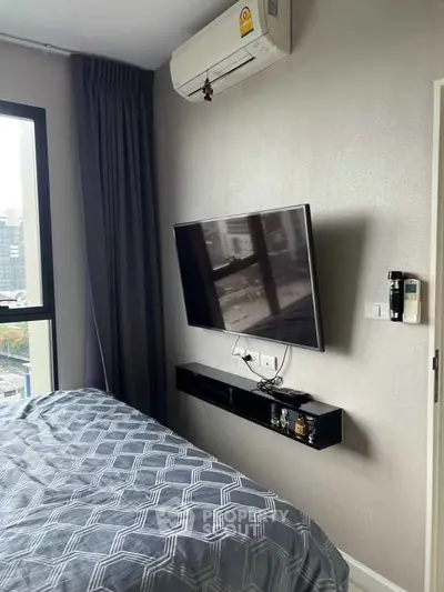 Modern bedroom with wall-mounted TV and city view, featuring sleek design and natural light.