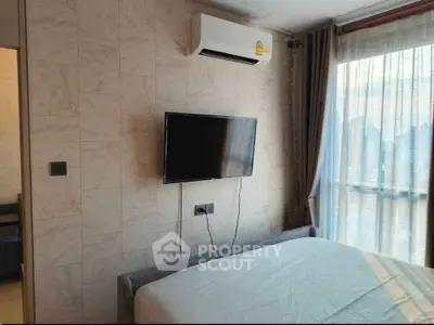 Cozy bedroom with wall-mounted TV and large window for natural light