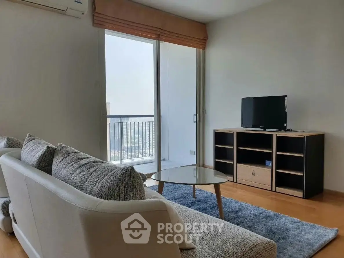 Modern living room with balcony view, stylish furniture, and natural light.