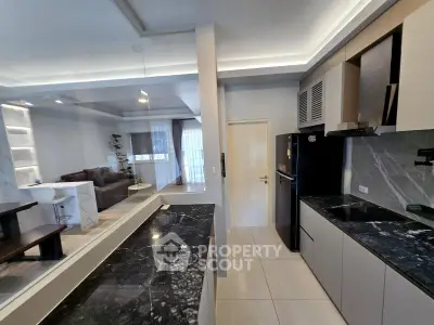 Modern open-layout kitchen with sleek black countertops and spacious living area view.