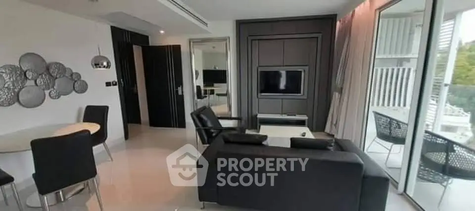 Modern living room with sleek black furniture and large windows offering natural light.