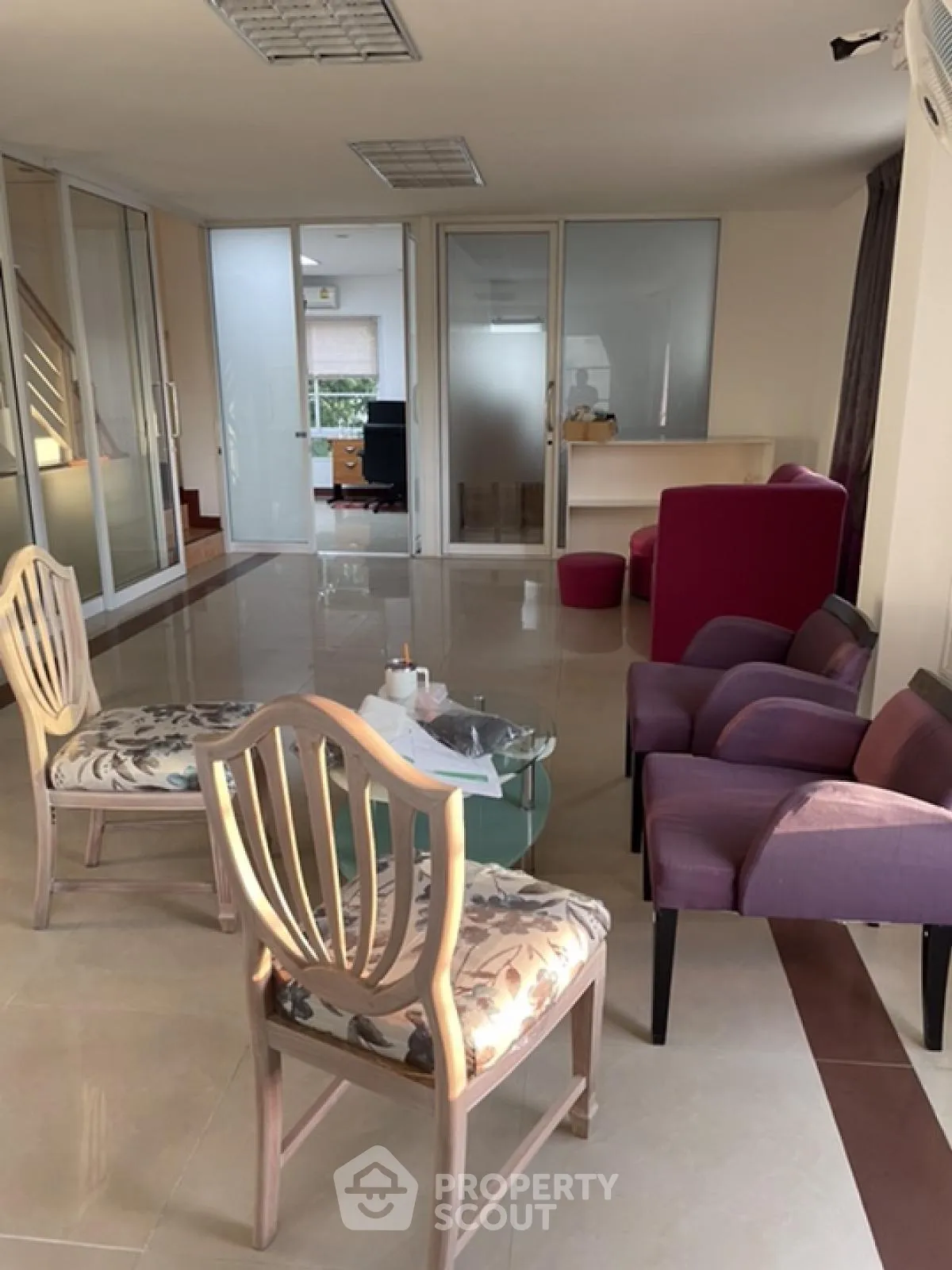 Spacious living area with elegant chairs and glass table, featuring modern design and ample natural light.