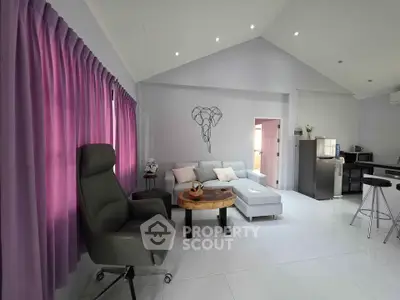 Spacious living room with modern decor and open kitchen layout, featuring elegant furniture and natural light.