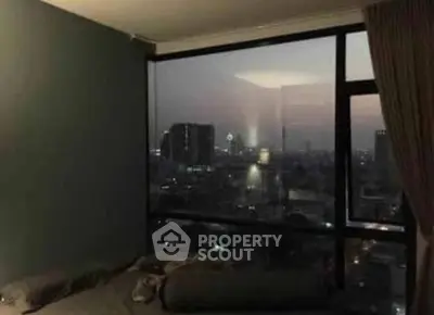 Cozy bedroom with stunning city skyline view through large window at dusk.